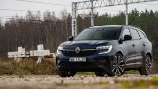 Nowy Renault Espace 6, ciemnoniebieski SUV, zaparkowany przy torach kolejowych.