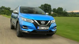 Niebieski Nissan Qashqai 1.6 benzyna jedzie po wiejskiej drodze, otoczony zielenią.