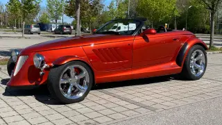 Pomarańczowy Plymouth Prowler, klasyk z lat 90., błyszczy na parkingu.