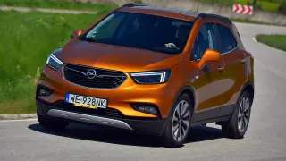 Pomarańczowy Opel Mokka 1.6 benzyna na zakręcie drogi.