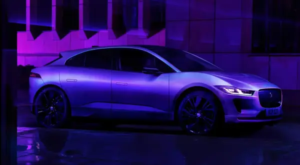 Elegancki jaguar elektryczny lśni w fioletowym świetle, gotowy na nocną jazdę.