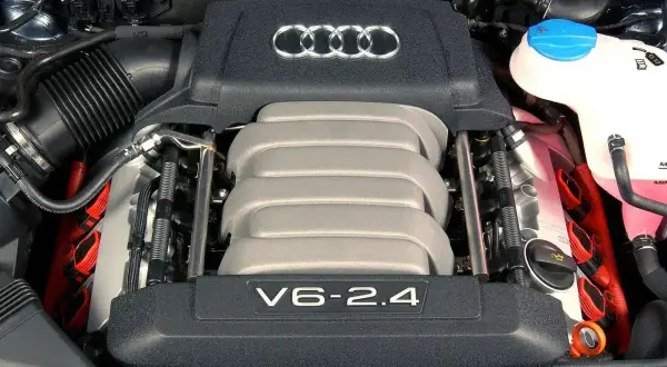 Silnik V6 2.4 benzyna z Audi A6 C6. Widoczne cewki zapłonowe i pokrywa silnika z logo Audi.