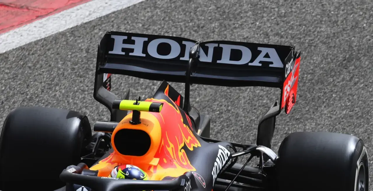 Wyścigówka Red Bulla z logo Honda na spojlerze pędzi po torze.