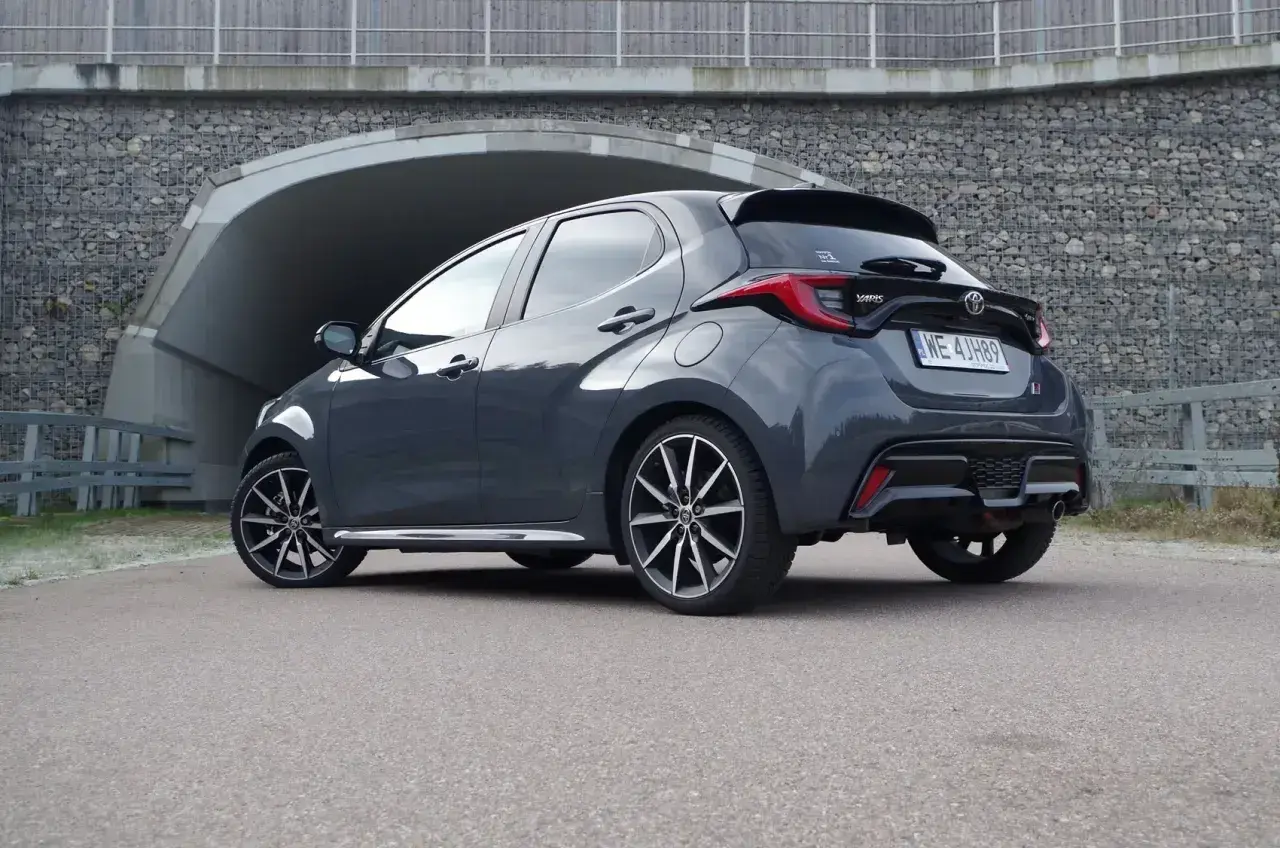 Szary Toyota Yaris Hybrid zaparkowany przed tunelem.