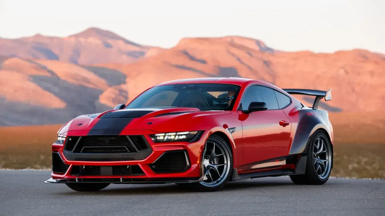 Czerwony Ford Shelby z czarnymi pasami i spojlerem na tle pustynnych gór.