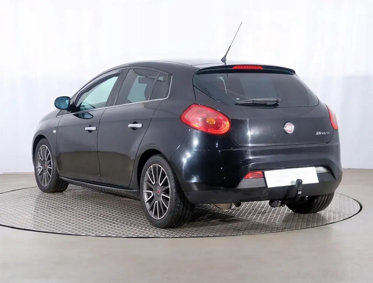 Czarny Fiat Bravo 1.4 T-Jet z przyciemnianymi szybami i felgami aluminiowymi, prezentowany na obrotowej platformie.