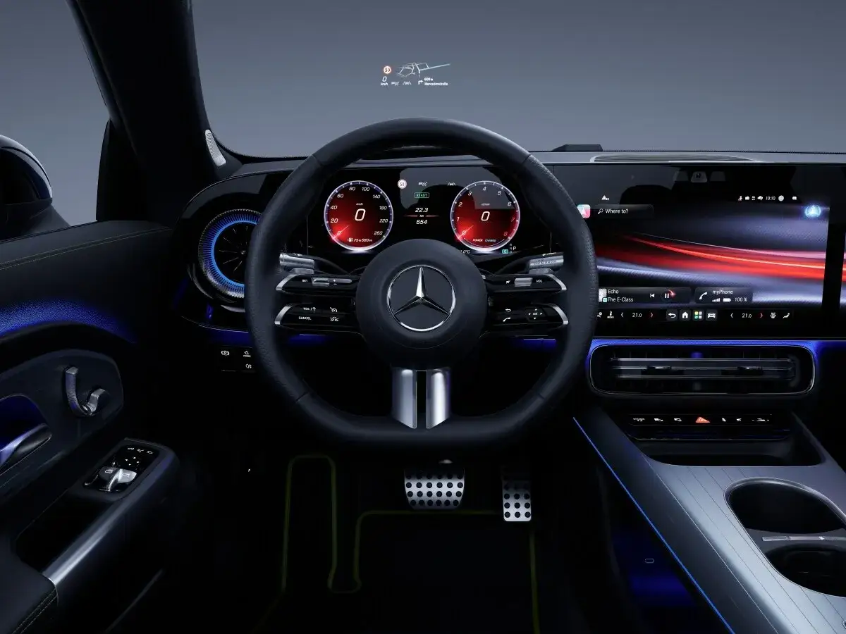 Wnętrze nowoczesnego Mercedesa CLA 180 z cyfrowymi zegarami, dużym ekranem multimedialnym i ambientowym oświetleniem.