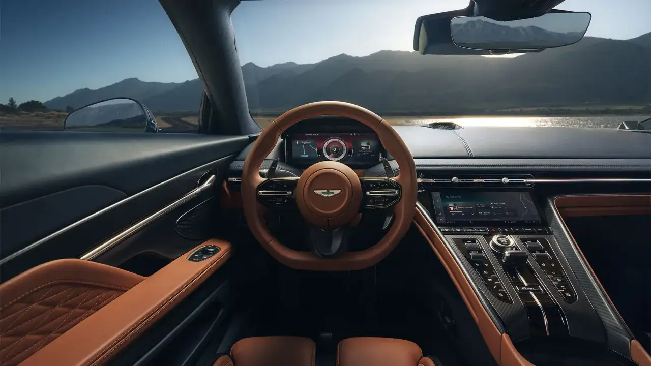 Wnętrze Aston Martin DBS z brązową skórzaną kierownicą i siedzeniami, nowoczesnym panelem i widokiem na góry.