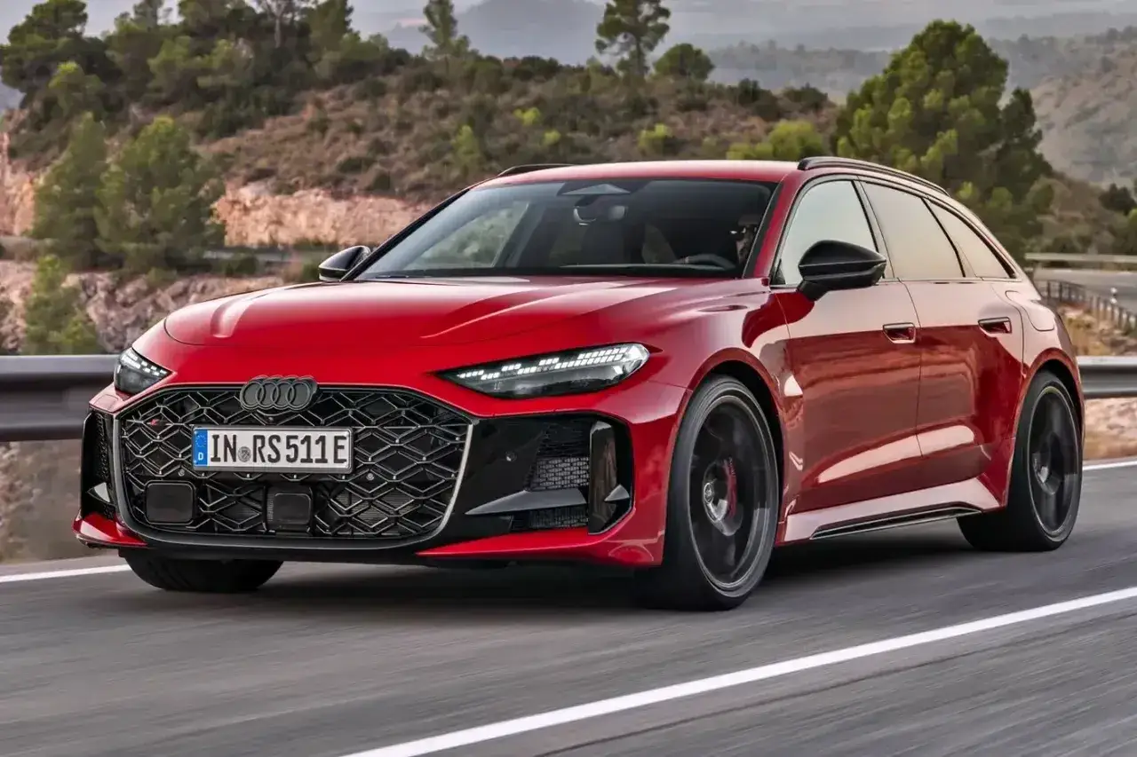 Czerwone Audi RS5 Avant 2026 pędzi po krętej drodze, otoczone malowniczymi wzgórzami.